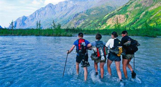 A group of hikers cross Eagle River while hiking the Crow Pass in the Chugach Mountains.