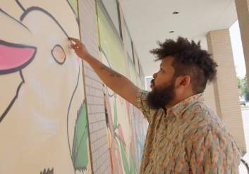 Artist Bisco works on a mural in downtown Anchorage.