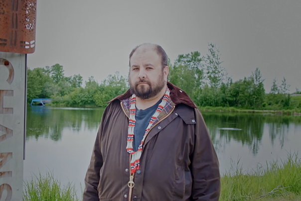 NVE President Aaron Leggett stands next to the Indigenous Place Names marker for Chanshtnu, at Westchester Lagoon.