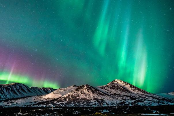 The northern lights, or aurora borealis, shimmer over the snow-covered Chugach Mountains east of Anchorage, Alaska.