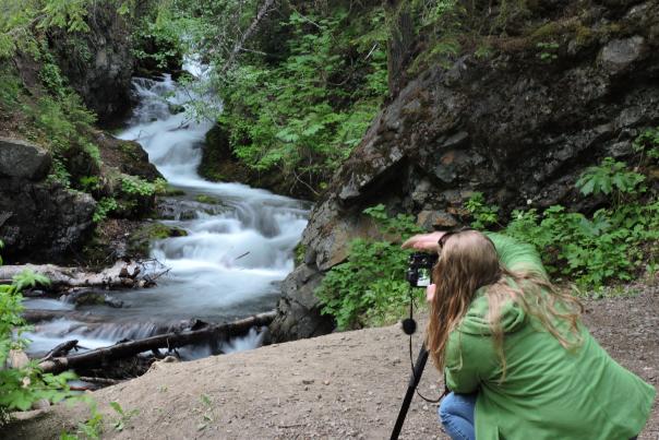 A woman snaps a photo of McHugh Creek on a photo tour throughout Anchorage.