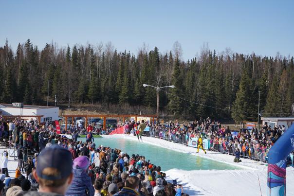 A skier in costume, floats across an icy pond at Hilltop Ski Area's Skim Sink or Swim in spring.