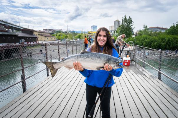 Girl holding a salmon at Ship Creek, Anchorage's urban fishery.
