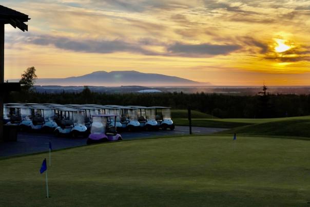 Golf carts are lined up at the Anchorage Golf Course as the evening summer sun glides over Mount Susitna.