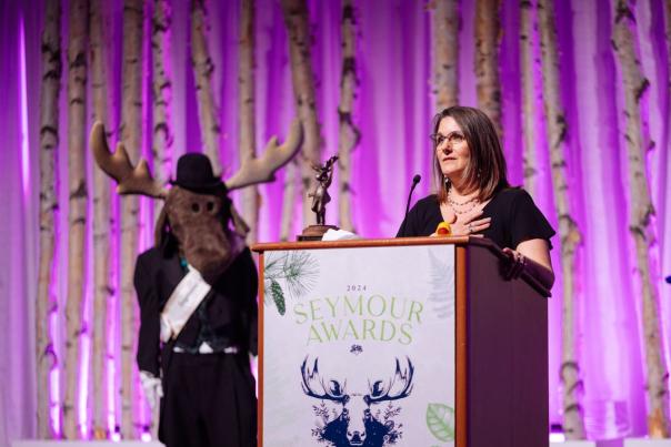 A person accepts an award at the annual Visit Anchorage Seymour Awards.