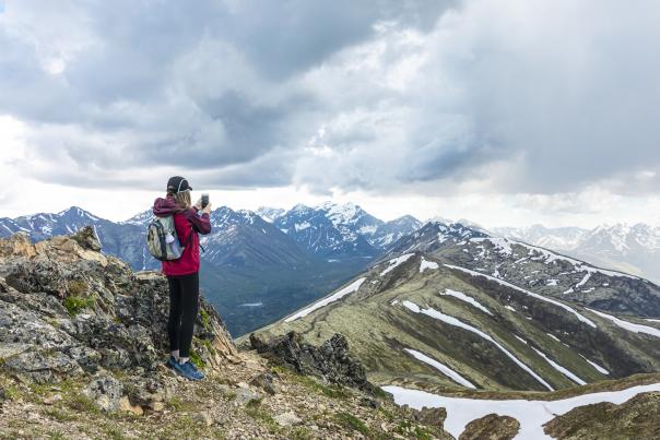 Hiker taking a photo from the top of the Chugach Mountain in Arctic Valley