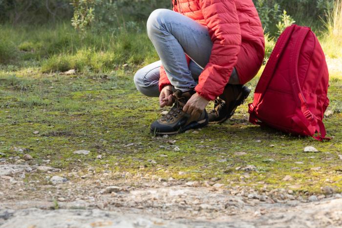 Hiker bending down to tie hiking boot before hitting the trails.