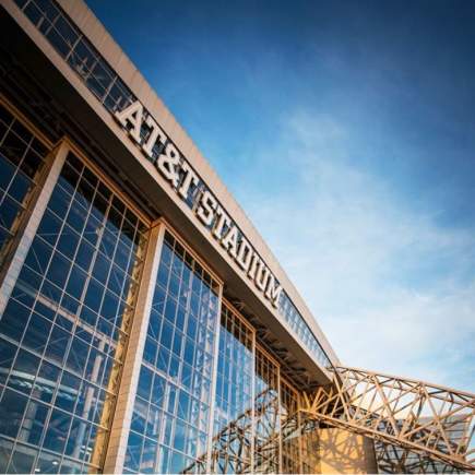 Photo of front of AT&T Stadium with sky reflection