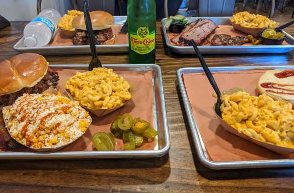 Photo of food trays at Hurtado Barbecue with sandwiches, corn and macaroni and cheese.