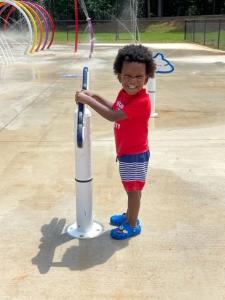 Adorable toddler boy plays at splash pad
