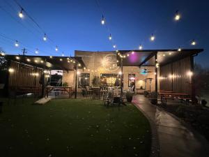 Green outdoor space in front of Paper Plane restaurant at dusk with string lights illuminated.