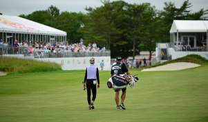 LPGA golf professional and caddy walk on the fairway with tented crowds watching the ShopRite LPGA at Seaview Golf Club in Galloway, NJ.