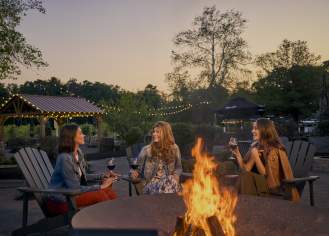 Three friends share wine around an outdoor fire pit at Renault Winery near Atlantic City.