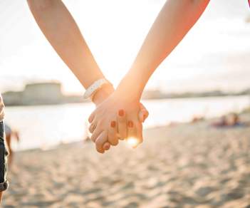 Two women holding hands on a stretch of beach in Atlantic City, NJ.