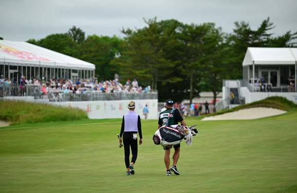 LPGA golf professional and caddy walk on the fairway with tented crowds watching the ShopRite LPGA at Seaview Golf Club in Galloway, NJ.