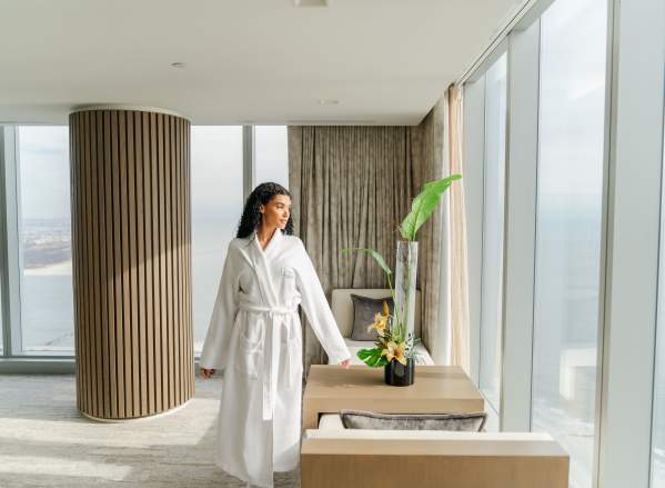 Woman relaxes in her hotel suite with floor to ceiling windows and ocean views at Ocean Casino Resort in Atlantic City NJ.
