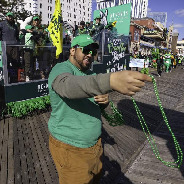 Man handing out green beaded necklaces as part of a float at the Atlantic City St. Patrick's Day Parade on the Atlantic City Boardwalk in 2025.