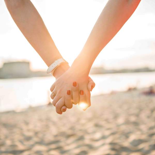 Two women holding hands on a stretch of beach in Atlantic City, NJ.