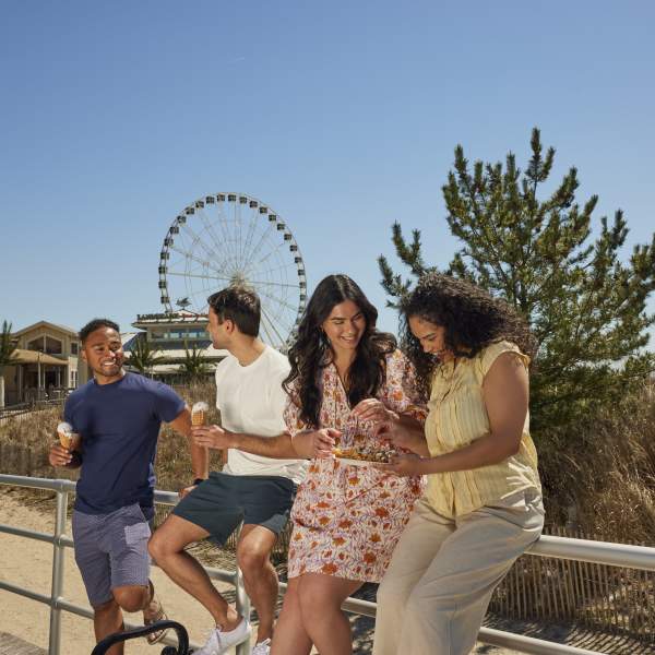 Group of four enjoying some boardwalk fare while relaxing on the Atlantic City Boardwalk.