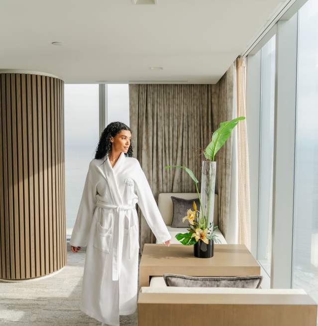 Woman relaxes in her hotel suite with floor to ceiling windows and ocean views at Ocean Casino Resort in Atlantic City NJ.