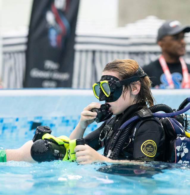 Girl with scuba gear in a  pool working with a guide at "Try Scuba" experience at the Scuba Show.