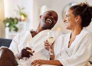 Two people laughing drinking Champagne in robes at a spa.