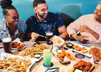 Adults laughing and enjoying drinks and bites at Dave & Buster's Atlantic City.