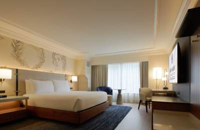 Hotel room at Caesars Atlantic City's Centurion Tower accommodations including a king size bed with warm woods and contemporary furnishings and window with view.