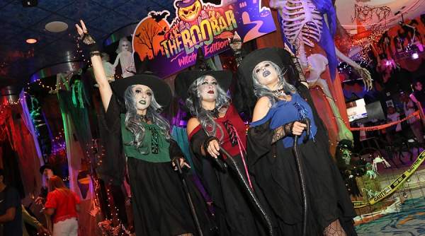 Three women dressed as witches pose in the foreground with Halloween decorations and a skeleton in the background at The Boo Bar at Resorts Casino Hotel in Atlantic City.