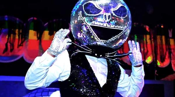 Mirror Man at Boogie Nights in Atlantic City. A person wearing a Disco ball mask with Halloween vibes and a sequined vest stands in the foreground against a dark background with colorful, blurred lights.