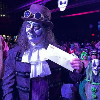 Person dressed up in a spooky costume holding an envelope at The Yard at Bally's Atlantic City during a Halloween party.