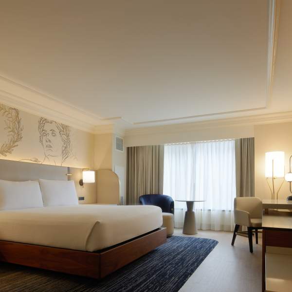 Hotel room at Caesars Atlantic City's Centurion Tower accommodations including a king size bed with warm woods and contemporary furnishings and window with view.