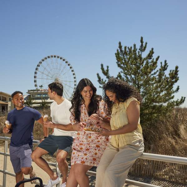 Group of four enjoying some boardwalk fare while relaxing on the Atlantic City Boardwalk.