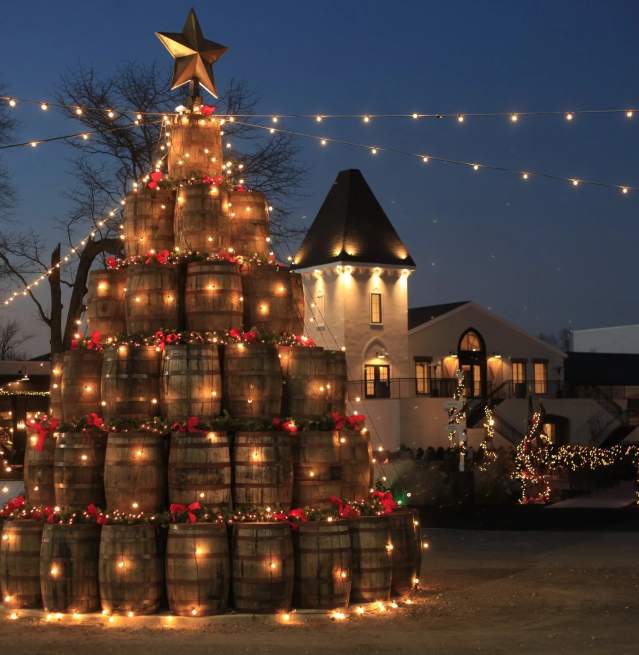 The Renault Winery and Resort Wine Barrel Tree seen at dusk decorated with lights and ornate red ribbons.