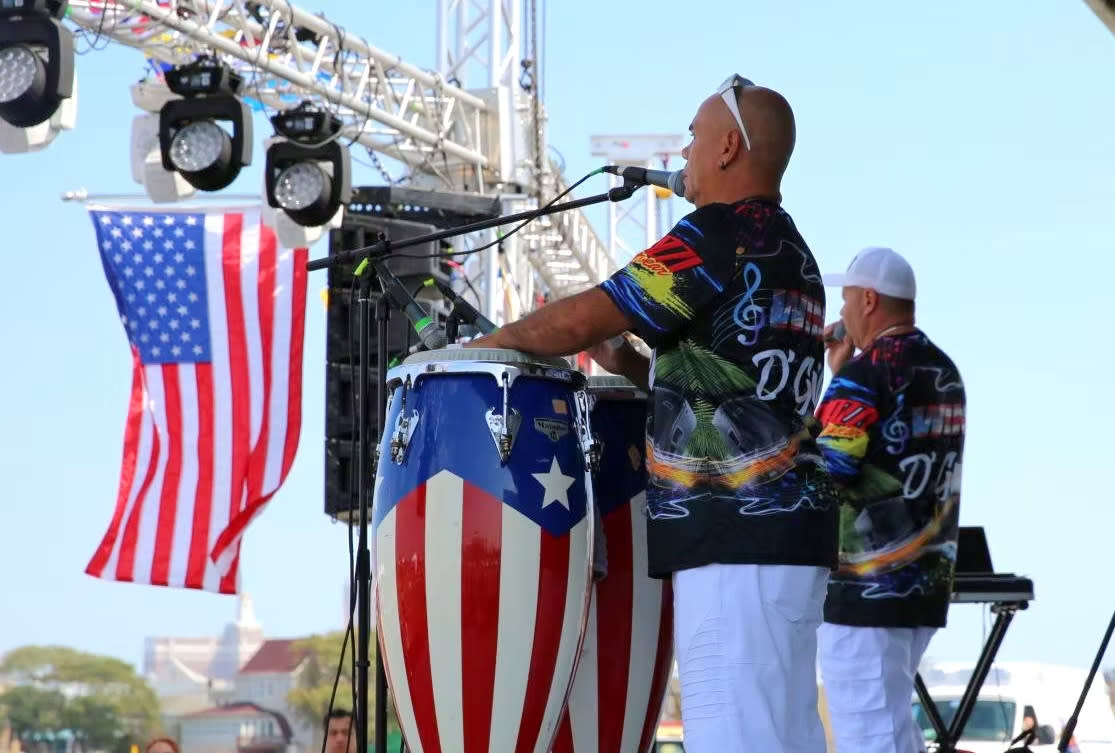 Two performers on stage at the Atlantic City Latino Festival with bongo drums decorated with the Puerto Rican flag.
