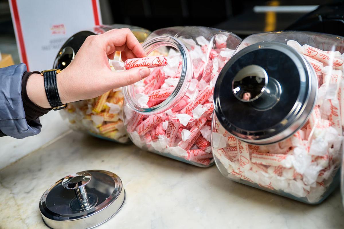 Person grabs a piece of salt water taffy from a jar