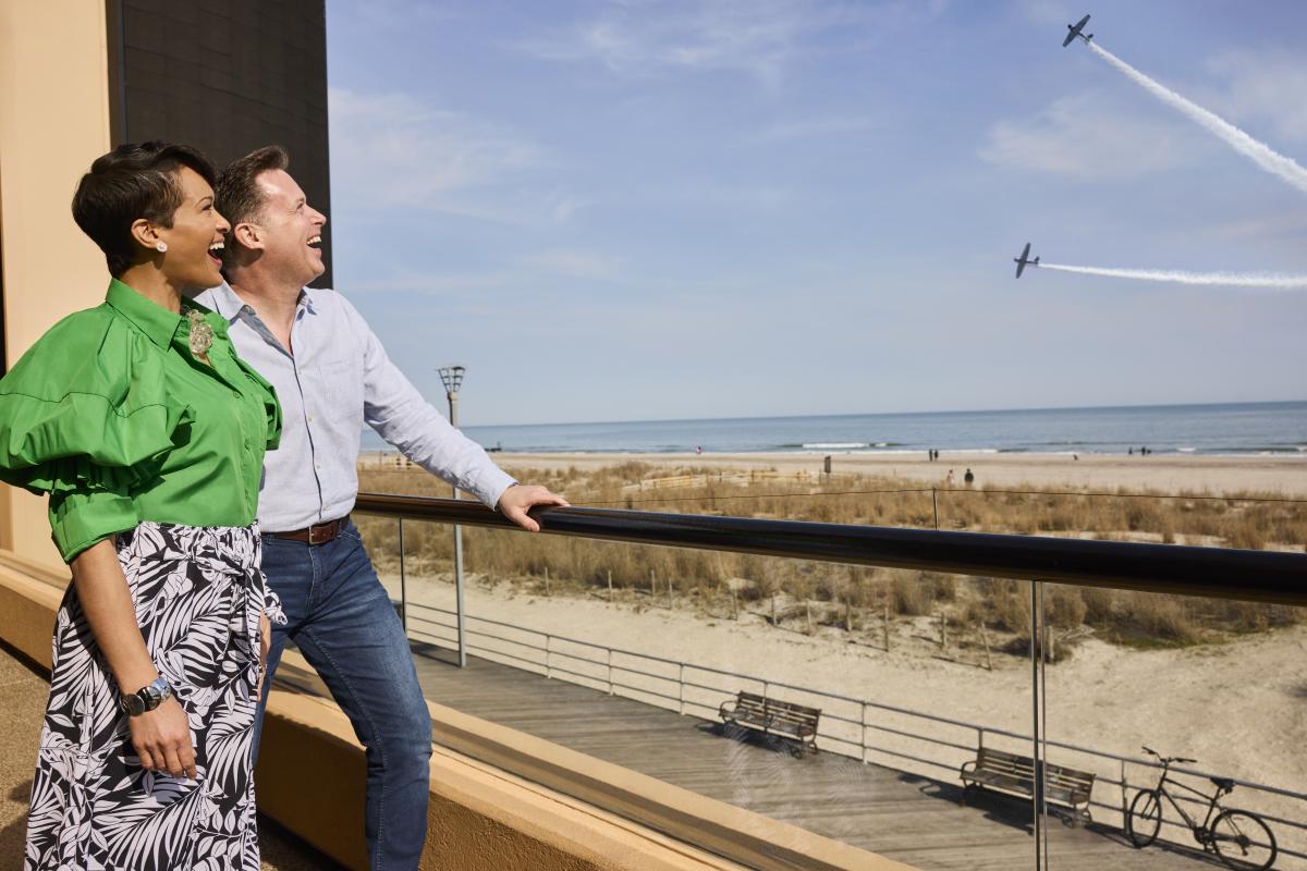 Air show planes flying above the Atlantic City shoreline as people watch from a balcony