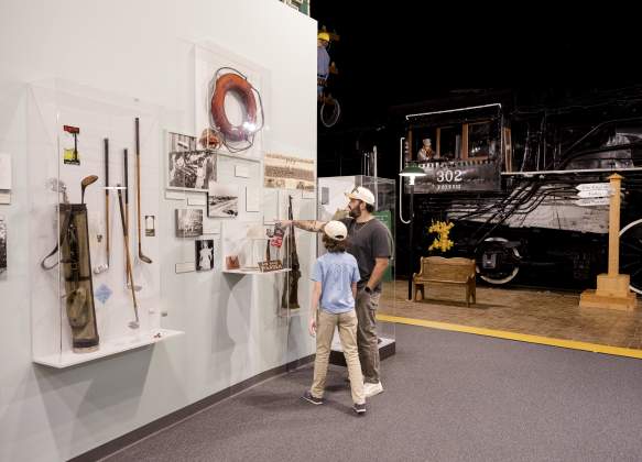Parent and child discover Augusta's history together while exploring museum exhibits featuring historic artifacts and a restored train engine.