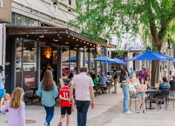 Family Walking Downtown with Trees and Outdoor Dining