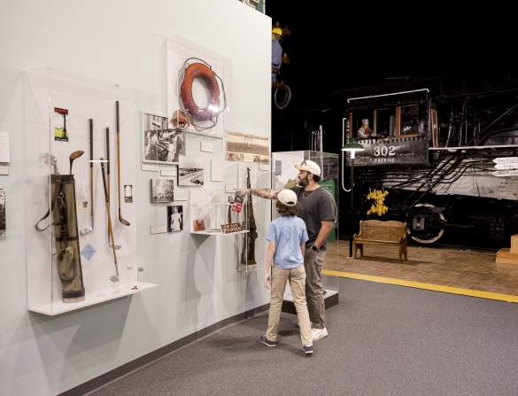 Parent and child discover Augusta's history together while exploring museum exhibits featuring historic artifacts and a restored train engine.