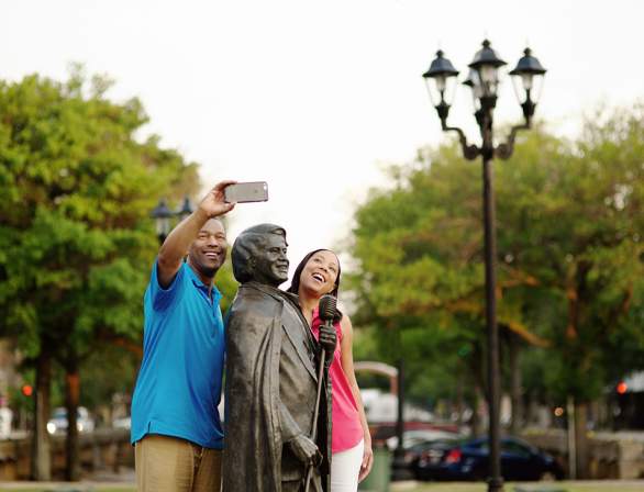 Couple taking a picture with James Brown's statue.