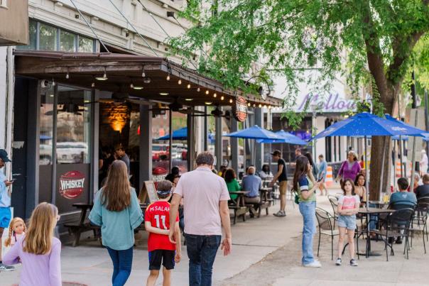 Family Walking Downtown with Trees and Outdoor Dining