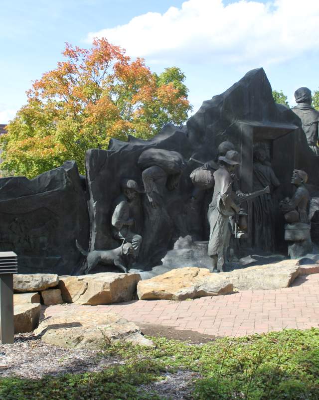 Underground Railroad Statue depicting bronze figures in motion, surrounded by vibrant trees and carefully maintained landscaping.