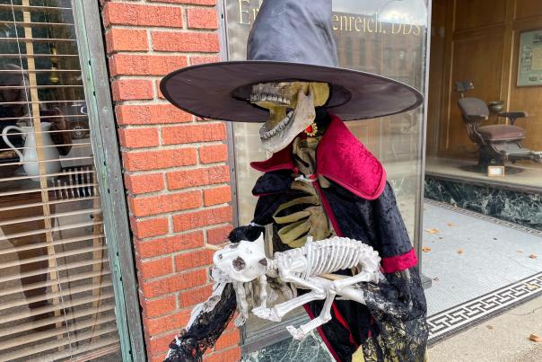 Every October, downtown Marshall has some silly, spooky fun with skeletons decorating stores and sidewalks. A skeleton dressed as a witch, holding a skeleton cat.
