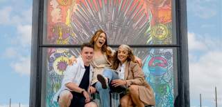 Group of three people posing for a phone at one of the stained glass windows on the Glass of Thrones Trail.