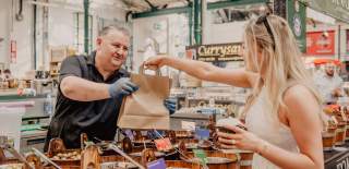 Woman buying some food goods from a seller at St George's Market
