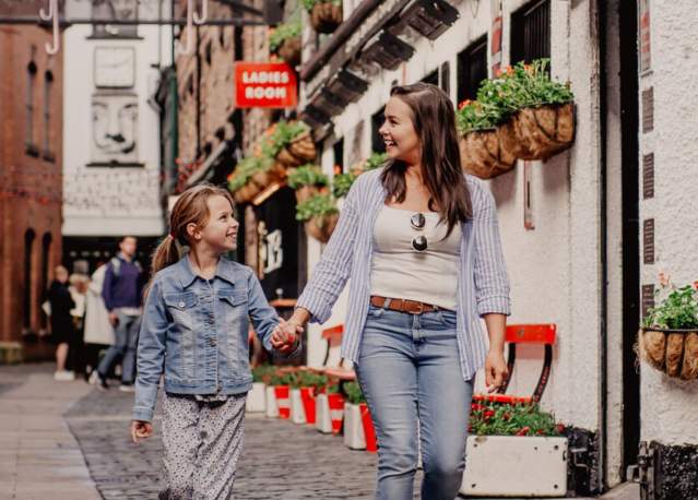 Mother and daughter holding hands walking through Commercial Court in Belfast