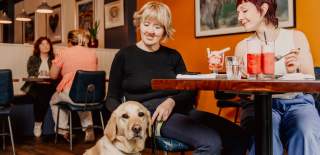 Two women and guide dog at a cafe