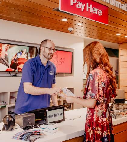 Man in Visit Belfast welcome centre helping tourists with information
