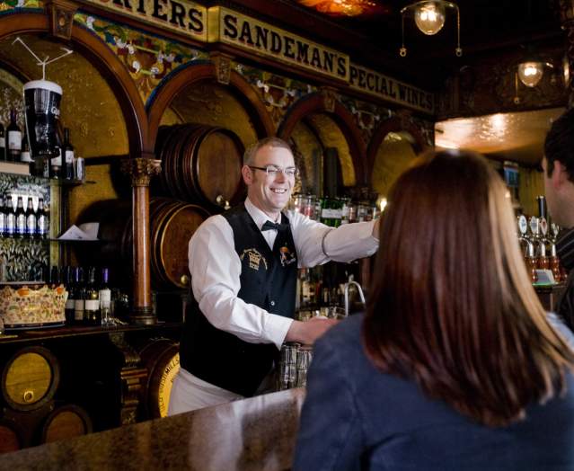 Barman in the Crown Liquor Saloon serving customers.